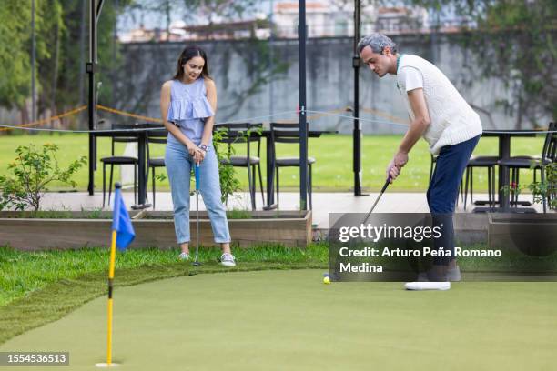couple playing mini golf - playing mini golf stock pictures, royalty-free photos & images