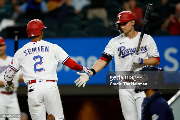 Marcus Semien is congratulated by Corey Seager of the Texas Rangers after hitting a solo home run against the Tampa Bay Rays in the third inning at...