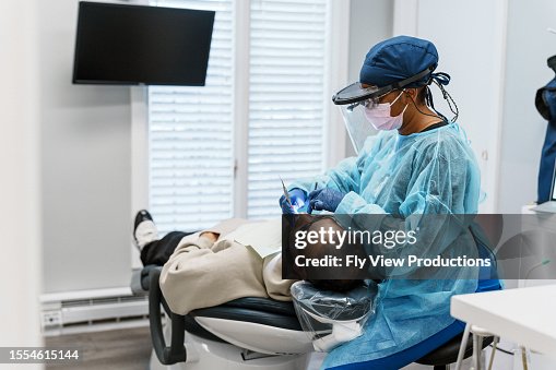 Female dentist performs a tooth filling on a patient Female dentist performs a tooth filling on a patient