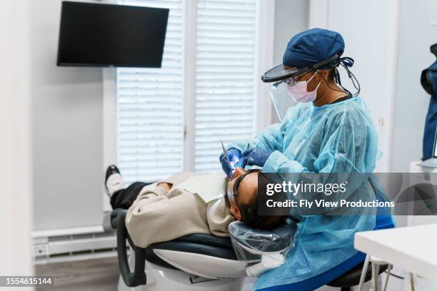 female dentist performs a tooth filling on a patient - dentist office stock pictures, royalty-free photos & images
