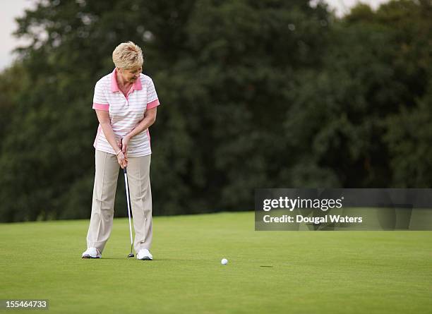 female golfer putting ball towards hole. - putting golf stock pictures, royalty-free photos & images