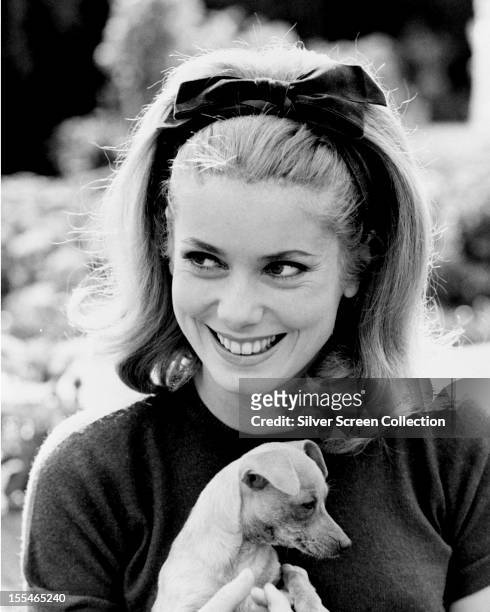 French actress Catherine Deneuve holding a puppy, circa 1962.