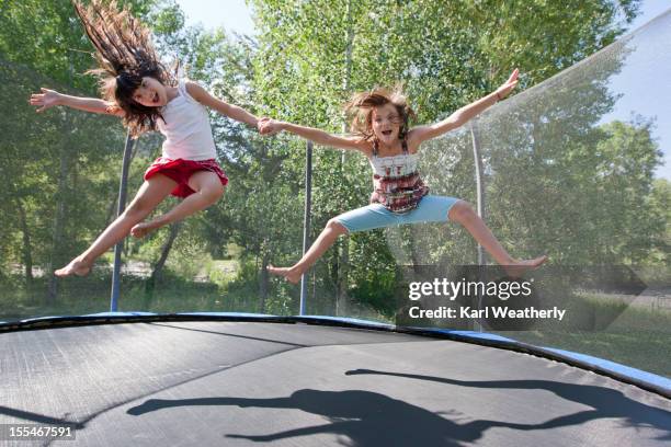 sisters jumping on a trampoline - trampoline equipment stock-fotos und bilder