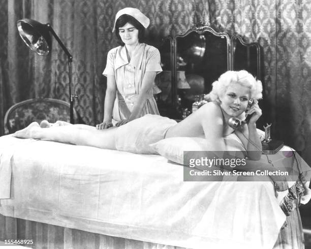 American actress Jean Harlow , as Ann Schuyler, makes a phone call, while being massaged in a publicity still for 'Platinum Blonde', directed by...