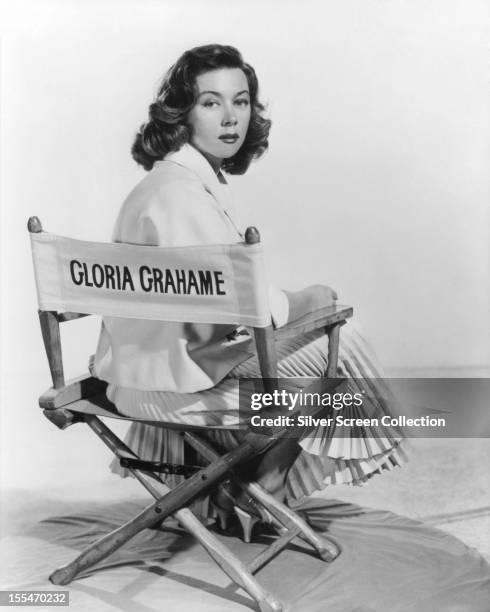 American actress Gloria Grahame sitting in a director's chair bearing her name, circa 1955.