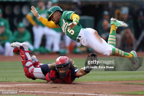 Tony Kemp of the Oakland Athletics jumps over Jorge Alfaro of the Boston Red Sox to try to score on a wild pitch in the first inning at RingCentral...