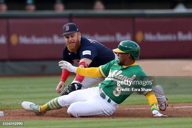 Tony Kemp of the Oakland Athletics slides safely past Justin Turner of the Boston Red Sox to reach third base safely in the first inning at...