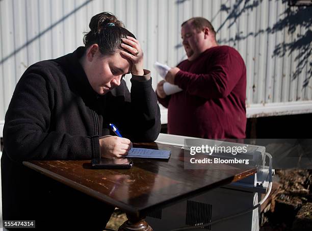 Cami Mazzarella pauses while compiling a list of her ruined belongings for a FEMA claim as her fiance Daniel Parker looks on outside their home in...