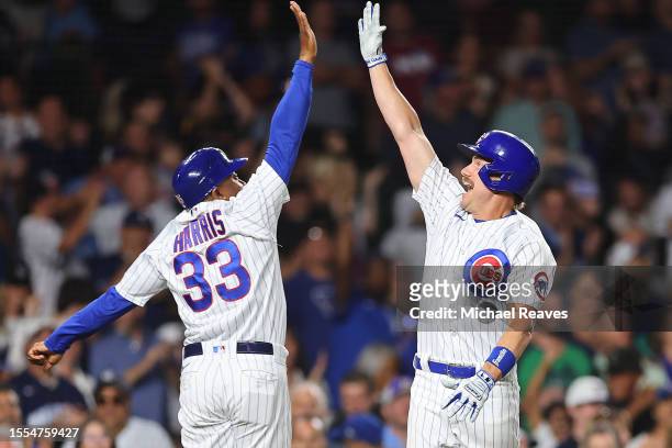 Patrick Wisdom of the Chicago Cubs high fives third base coach Willie Harris after hitting a solo home run off Amos Willingham of the Washington...