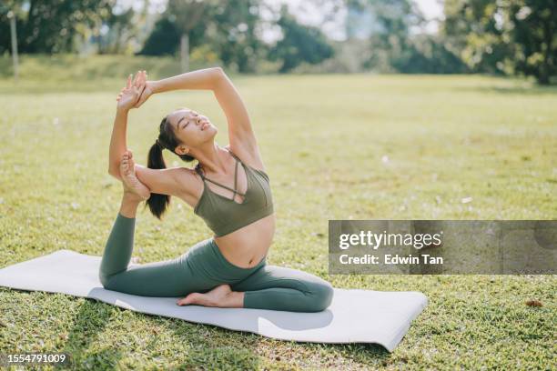 asian chinese woman practicing yoga stretching in public park weekend morning - upright position stock pictures, royalty-free photos & images