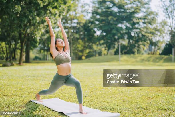 asian chinese woman sun salutation practicing yoga in public park weekend morning - sun salutation stock pictures, royalty-free photos & images