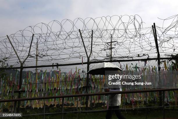 Woman walks past prayer ribbons wishing for reunification of the two Koreas on the wire fence at the Imjingak Pavilion, near the demilitarized zone...