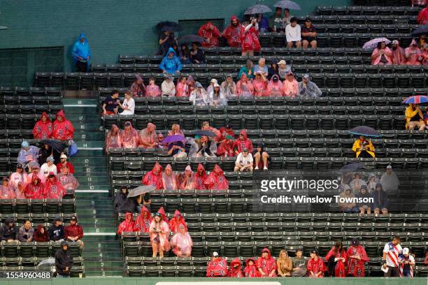 Fans sit in the bleachers during a rain delay at the start of the game between the Boston Red Sox and the Atlanta Braves at Fenway Park on July 25,...
