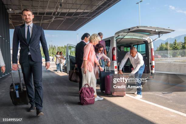 diverse people collecting luggage out of an airport shuttle van - shuttle bus stock pictures, royalty-free photos & images