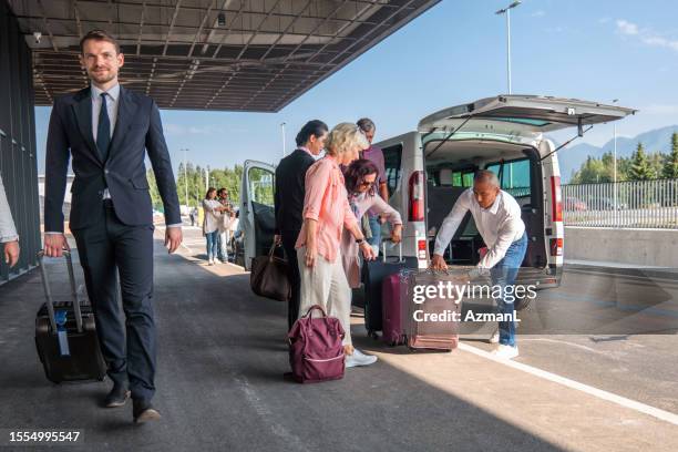 diverse people collecting luggage out of an airport shuttle van - airport bus stock pictures, royalty-free photos & images