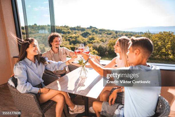 dos parejas felices que pasan tiempo juntas de vacaciones, bebiendo vino en el balcón - double date fotografías e imágenes de stock