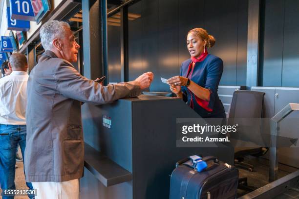 mid adult hispanic airline stewardess at the airport check in counter - check in person stock pictures, royalty-free photos & images
