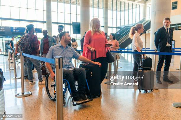 disabled caucasian male in a check in line at the airport lobby - lobbying stock pictures, royalty-free photos & images