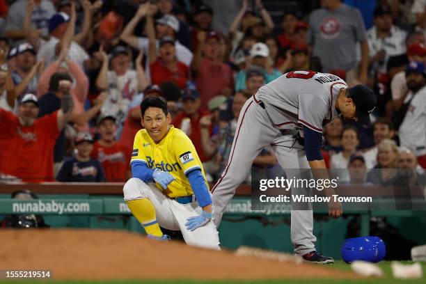 As pitcher Charlie Morton of the Atlanta Braves goes to pick up his helmet, Masataka Yoshida of the Boston Red Sox kneels at third base after making...