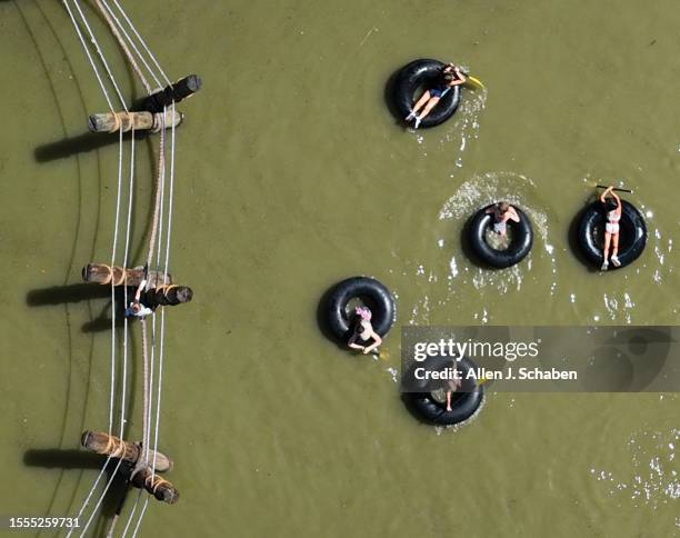 Huntington Beach, CA Kids play on a rope bridge and paddle inner tubes on a small pond at Adventure Playground amidst a hot day in Huntington Central...