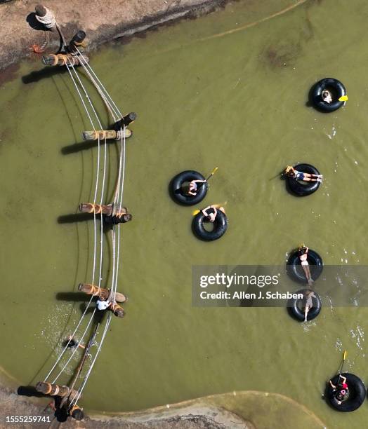 Huntington Beach, CA Kids play on a rope bridge and paddle inner tubes on a small pond at Adventure Playground amidst a hot day in Huntington Central...