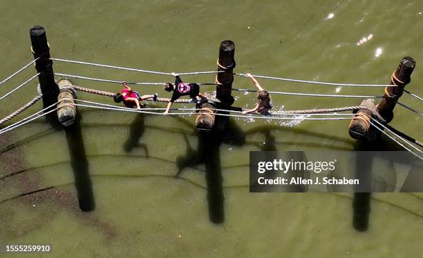 Huntington Beach, CA Kids play on a rope bridge on a small pond at Adventure Playground amidst a hot day in Huntington Central Park in Huntington...