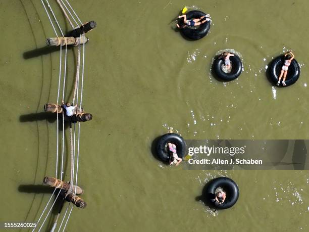 Huntington Beach, CA Kids play on a rope bridge and paddle inner tubes on a small pond at Adventure Playground amidst a hot day in Huntington Central...