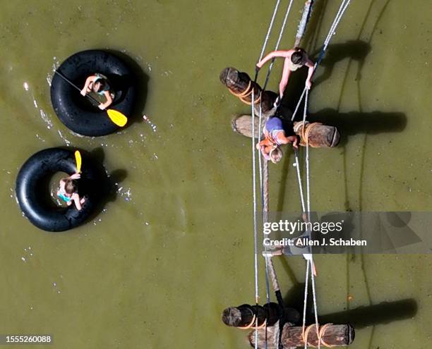 Huntington Beach, CA Kids play on a rope bridge and paddle inner tubes on a small pond at Adventure Playground amidst a hot day in Huntington Central...