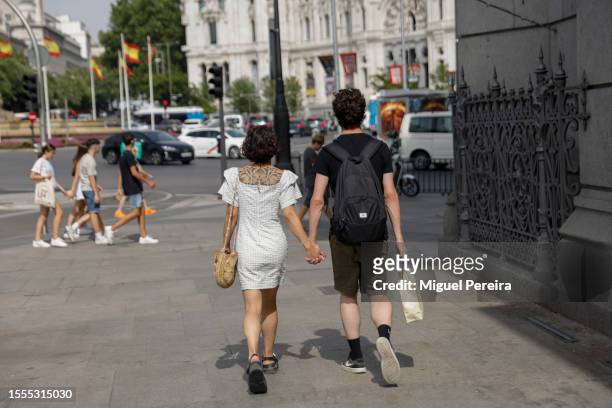Couple stroll down Alcalá street towards Plaza de Cibeles on a very hot afternoon on July 18, 2023 in Madrid, Spain. An area of high pressure, named...