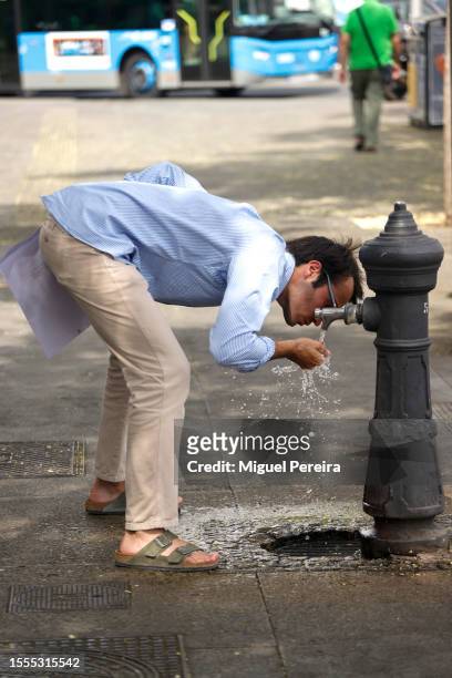 Man drinks water from a public fountain on Paseo de la Castellana on a very hot afternoon on July 18, 2023 in Madrid, Spain. An area of high...