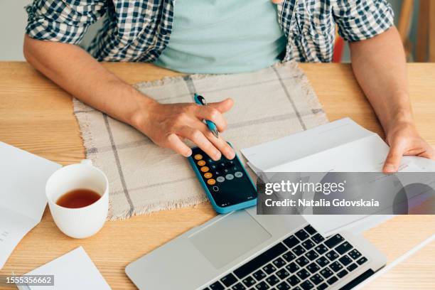 man using calculator, analyzing financial data. focused on work and working on budget or expense report. man sitting at table in well-lit office. - modulo per la dichiarazione dei redditi foto e immagini stock