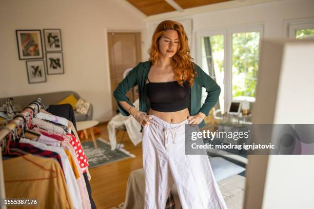 giovane donna che prova una camicia che ha scelto nella sua camera da letto a casa - provare foto e immagini stock
