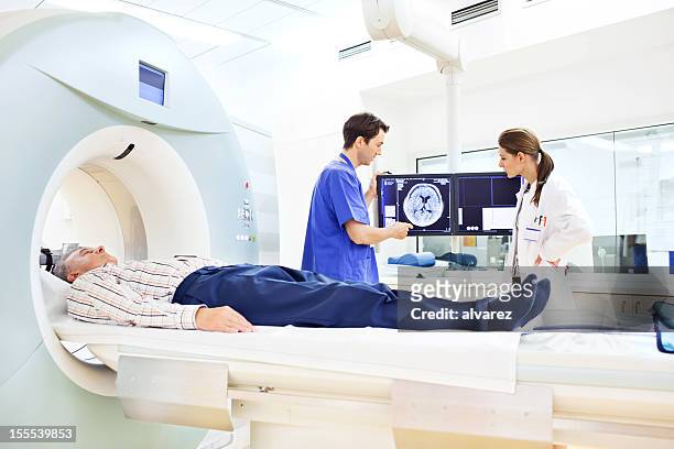 ärzte diskutieren eine cat-scan - magnetresonanztomographie stock-fotos und bilder