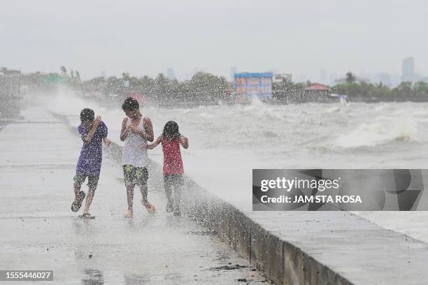 Children walk along a sea wall at Navotas in Metro Manila on July 26 as Super Typhoon Doksuri passes close to the northern tip of Luzon island.