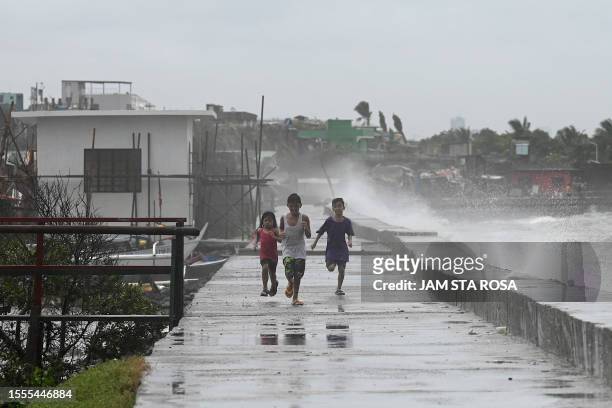 Children walk along a sea wall at Navotas in Metro Manila on July 26 as Super Typhoon Doksuri passes close to the northern tip of Luzon island.