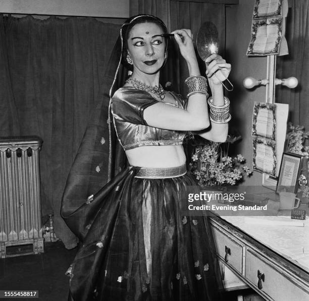 Ballerina Alicia Markova applies makeup in her dressing room while dressed in Indian saree stage costume, March 17th, 1958.