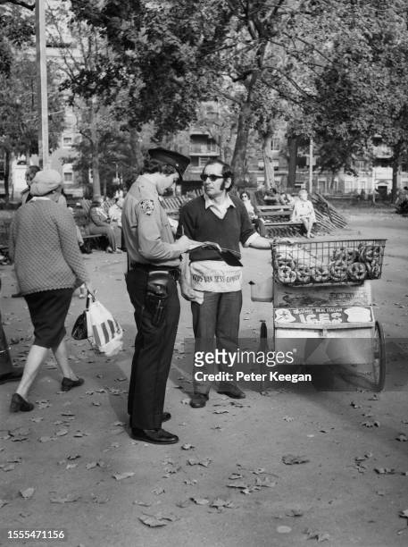 An NYPD police officer fines a pushcart pretzel vendor in Washington Square Park, in the Greenwich Village neighbourhood of Lower Manhattan, in New...