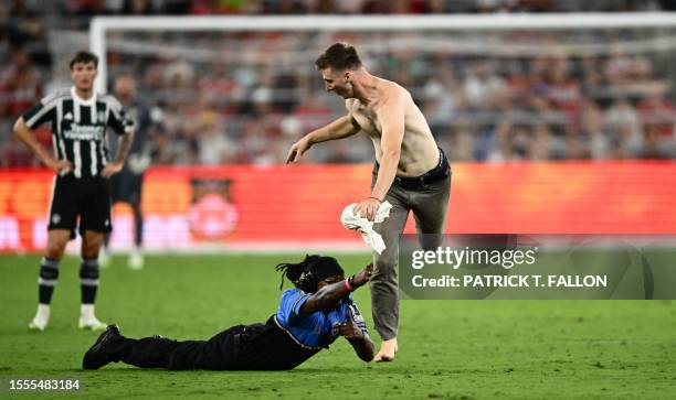 Security guard attempts to tackle a fan running on the pitch at the end of a pre-season friendly football match between Manchester United and Wrexham...