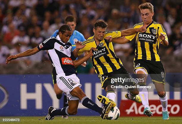 Jonathan Bru of the Victory contests with Vince Lia and Tyler Boyd of the Phoenix during the round five A-League match between the Melbourne Victory...