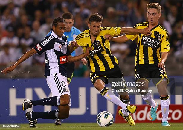 Jonathan Bru of the Victory contests with Vince Lia and Tyler Boyd of the Phoenix during the round five A-League match between the Melbourne Victory...
