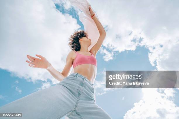 a beautiful asian woman with curly hair is dancing, waving a white cloth, wide angle shot from below - guess jeans stock pictures, royalty-free photos & images