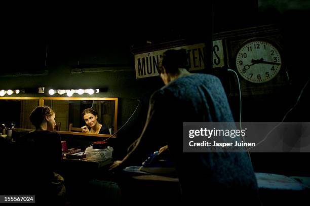 Actress Maria Pastor does her make-up backstage besides actress Alicia Gonzalez ironing her dress for the 'Tres Anos' theater show, a show that plays...