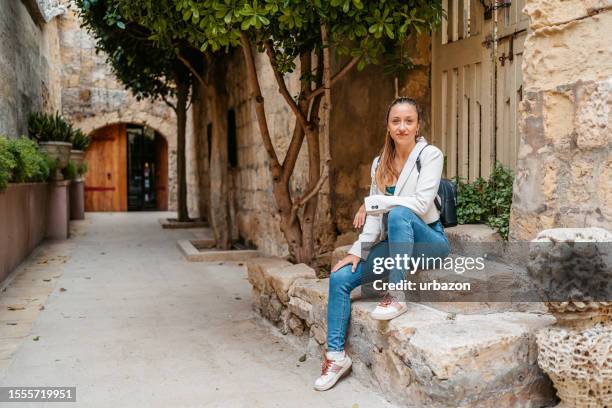 young woman sitting on the steps in mdina in malta - modern malta stock pictures, royalty-free photos & images