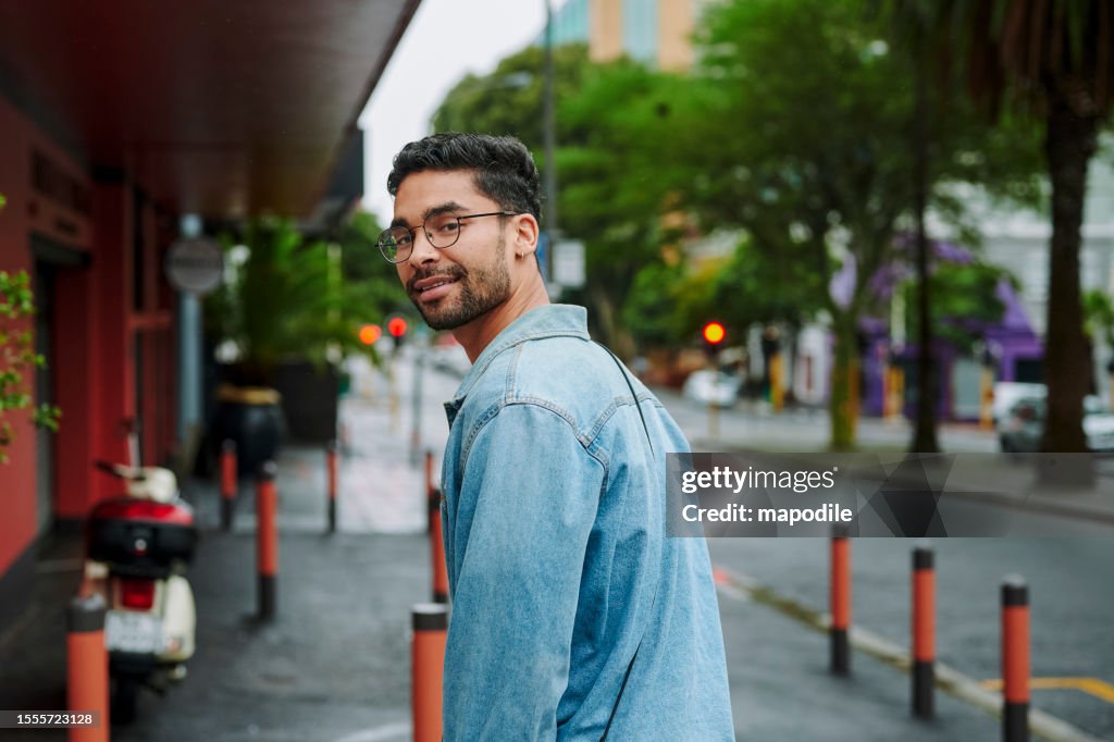 Smiling young man looking over his shoulder while walking in the city