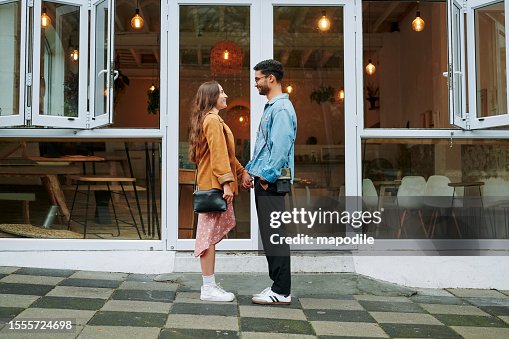 Loving young couple standing face to face in front of a cafe Loving young couple standing face to face in front of a cafe