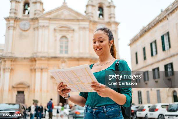young female tourist reading a map in front of st paul's cathedral in mdina in malta - mdina stock pictures, royalty-free photos & images