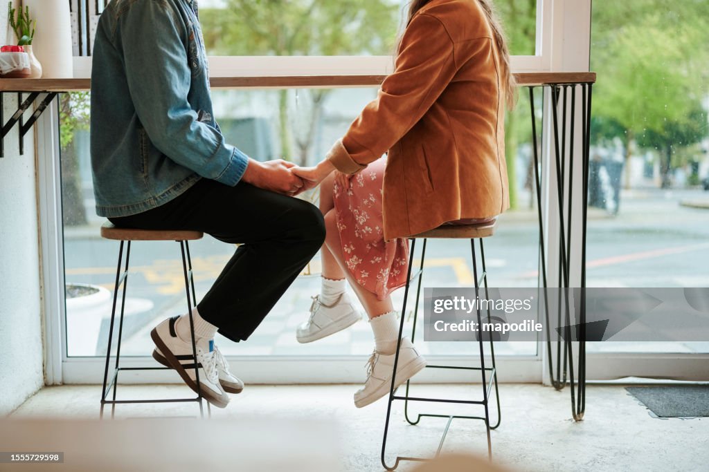 Pareja joven sentada en un café y tomados de la mano durante una cita