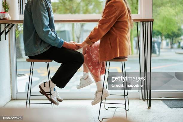 jeune couple assis dans un café et se tenant la main lors d’un rendez-vous - allumer photos et images de collection