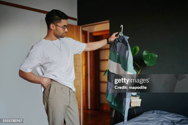 young man trying to choose an outfit before a date - hålla ovanför huvudet bildbanksfoton och bilder