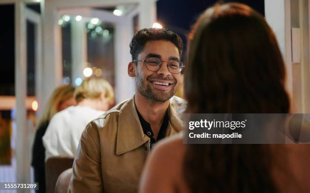 young man laughing while on a date with a young woman in the evening - encontro entre desconhecidos imagens e fotografias de stock